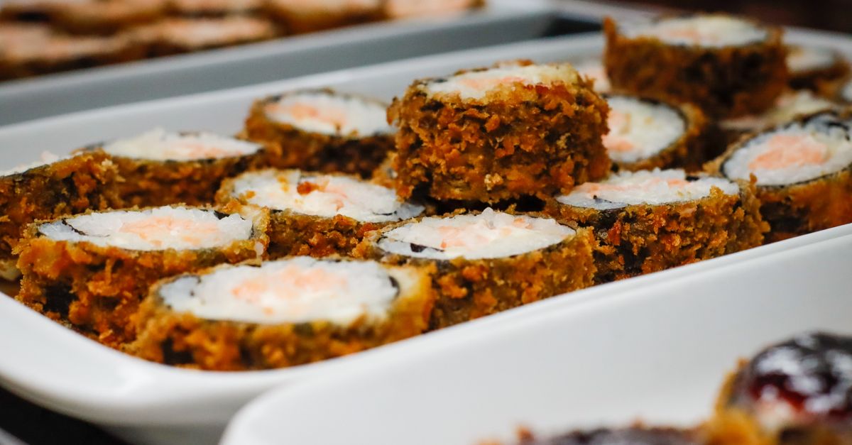A close-up of crispy fried sushi rolls presented elegantly on a white tray.